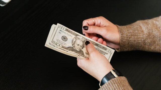 person counting money next to car representing auto repair cost savings